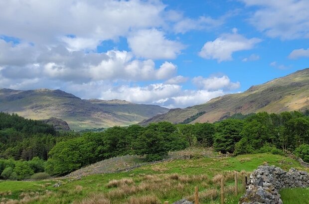 Dry stone wall in foreground of image showing the Upper Duddon Valley under blue skies