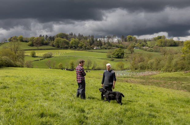 Two men and a dog stand in the Axe landscape