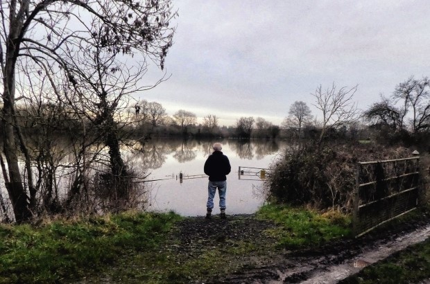 Farmer stands alone looking at flooded field in aftermath of Storm Henk 2024