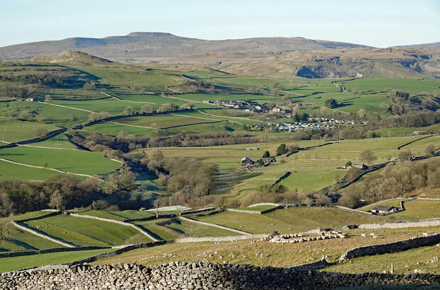 Ingleborough Above Ribblesdale
The river, green pastures and stone walls below the limestone and gritstone moors and fells. Also a large static caravan site at Little Stainforth and sheep forming a circle.