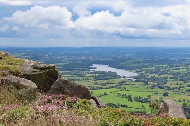 Photo taken from high ground. The sun lighting the rocks, heather and the pastures surrounding Tittesworth Reservoir.