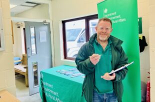 Giles Hall, from the Engagement Team, holding a clipboard in an indoors setting