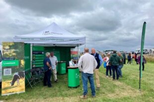 A Defra stand with people standing by it in conversation under a grey sky.
